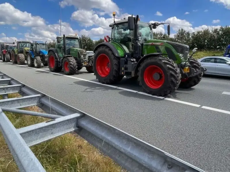 Una fila di trattori attraversa un'autostrada, un'immagine che ricorda che sulle autostrade e strade extraurbane principali è vietata la circolazione di macchine agricole.
